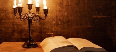 open-holy-bible-candle-old-oak-wooden-table-beautiful-gold-background-religion-concept (1)